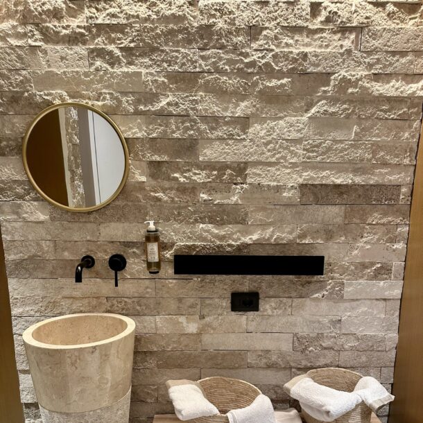 Bagno con parete in travertino e lavabo in pietra